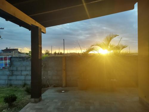 um pôr-do-sol sobre uma cerca com uma palmeira em Cantinho do Manolo em Laguna