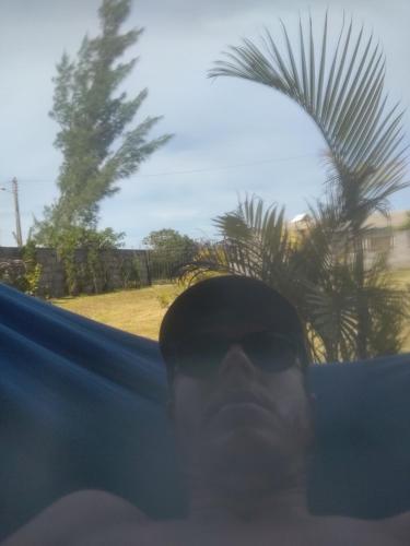 un hombre con gafas de sol y una palmera en el fondo en Cantinho do Manolo en Laguna