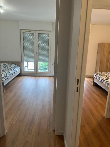 Cette chambre vide dispose de 2 lits et de parquet. dans l'établissement APPARTEMENT T2 Place Carnot, à Romainville
