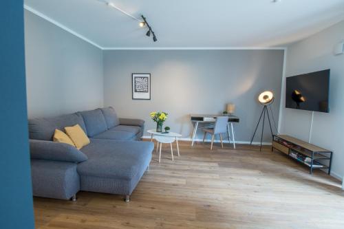 - un salon avec un canapé bleu et une table dans l'établissement Hygge Homes - 3 Zimmer Apartment, barrierefrei mit Terrasse, à Scharmbeck