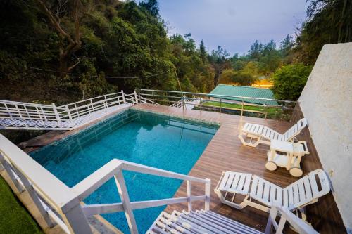 an overhead view of a swimming pool with two chairs and a table at Little Heaven - Cabin 2 in Rājpur
