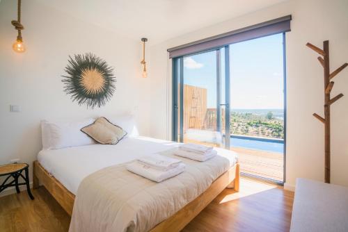 una camera da letto con un letto e una grande finestra di Caju Villas Montargil - Villa Terra Preta a Montargil