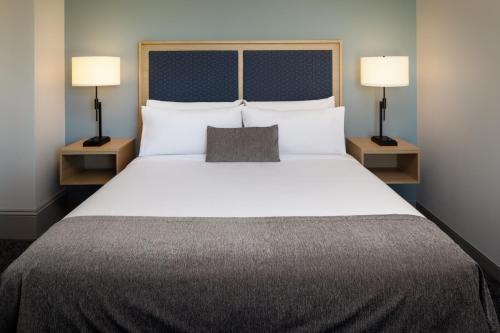 a bedroom with a large white bed with two lamps at Hotel Ursa in Orono