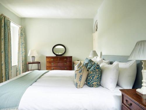 um quarto com uma grande cama branca com almofadas em Northfield End Cottage em Henley on Thames