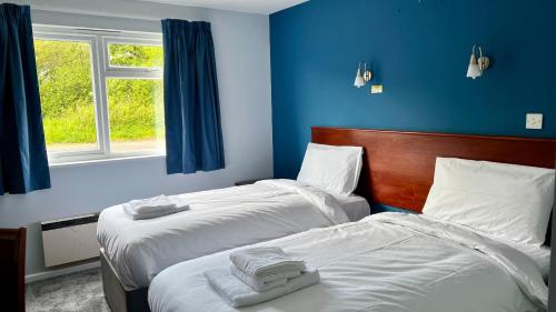 two beds in a room with blue walls at MK Hotel in Stony Stratford