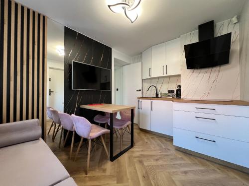 a kitchen with white cabinets and a table and chairs at Migor Apartamenty in Łeba