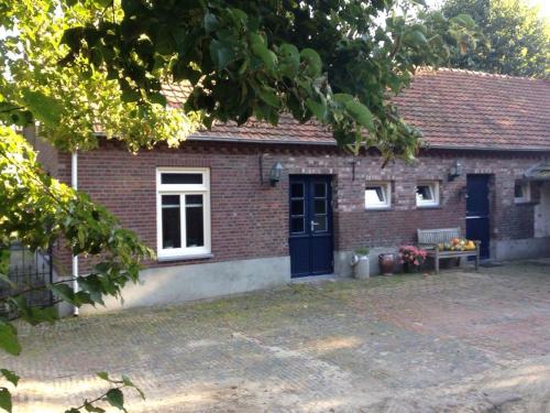 a brick house with a blue door and windows at Op Geneijgen in Grathem
