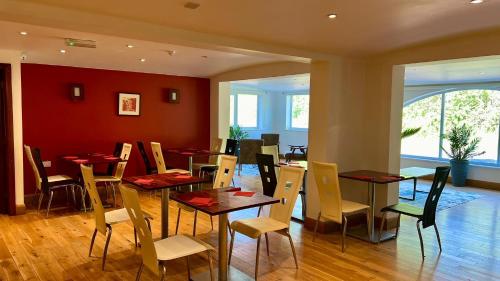 a dining room with tables and chairs and a red wall at MK Hotel in Stony Stratford