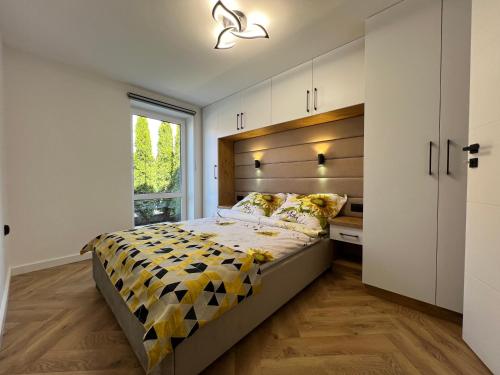 Un dormitorio con una cama grande y una ventana en Migor Apartamenty en Łeba