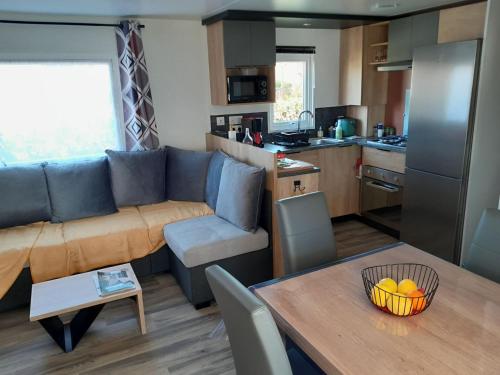 un salon et une cuisine avec un canapé et une table dans l'établissement location mobil home neuf, vue mer, tout confort, 6 personnes, à Saint-Jean-dʼOrbetiers