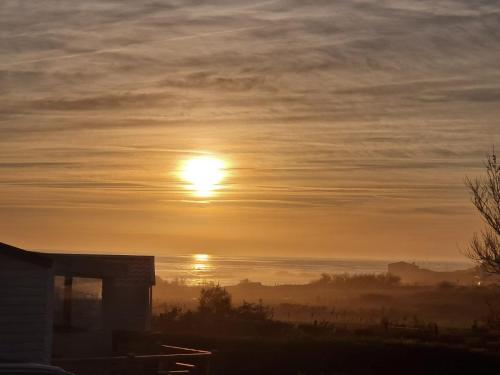 Un lever de soleil brumeux avec le soleil dans le ciel dans l'établissement location mobil home neuf, vue mer, tout confort, 6 personnes, à Saint-Jean-dʼOrbetiers