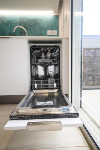 a dishwasher in a kitchen with its door open at Cocoonhuts Résidences Martinique in Le Lamentin