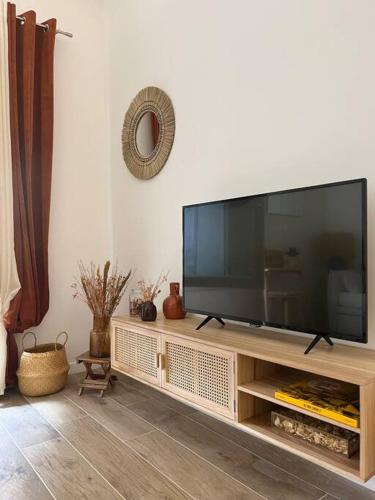 - une grande télévision à écran plat sur un centre de divertissement en bois dans l'établissement Duplex chaleureux et élégant à deux pas de la mer, à Marseille