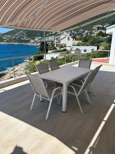 a table and chairs on a patio with a view of the ocean at Apartmani Stikovic in Dobra Voda