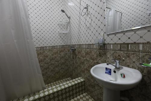 La salle de bains est pourvue d'un lavabo et d'une douche. dans l'établissement Boysun palace, à Baysun