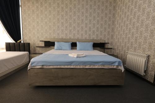 - une chambre dotée d'un grand lit avec des draps bleus dans l'établissement Boysun palace, à Baysun
