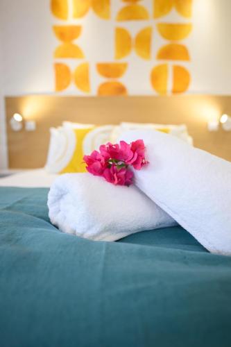 a white towel with a flower on top of a bed at Cocoonhuts Résidences Martinique in Le Lamentin
