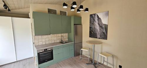 une cuisine avec des armoires vertes, une table et des chaises dans l'établissement Lägenhet Ateljén, à Hudiksvall