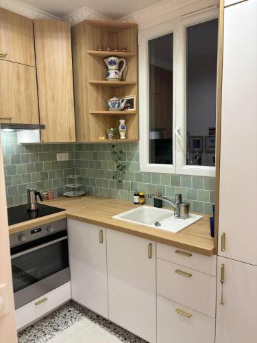 une cuisine avec des armoires blanches et un évier dans l'établissement Cute apartment near Paris-JO 24, à Colombes