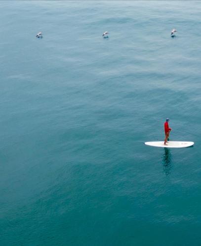 a man standing on a surfboard in the water at Hermanos Perdidos Surf in Las Tunas