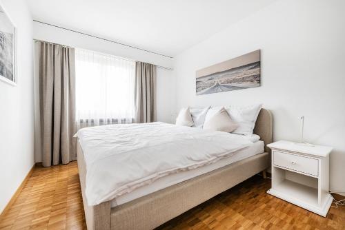 a white bedroom with a large bed and a window at Cooldis 9 !Gratis Parken, Free Parking! in Kreuzlingen