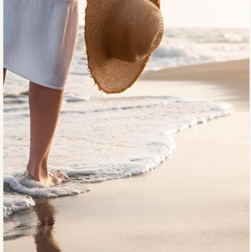 a woman wearing a straw hat walking on the beach at SanPietro Vacation Apartments in Durrës