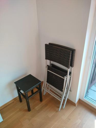 een stoel en een kruk in een kamer met een raam bij Garden View Triple Room - Neusiedlersee in Breitenbrunn