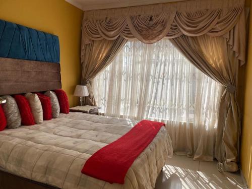 um quarto com uma cama grande e uma janela em Moyo's Guest House em Krugersdorp