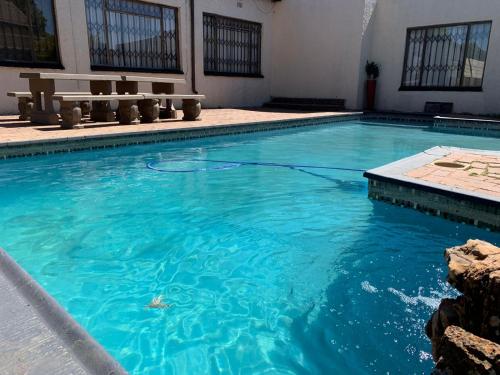 uma piscina com água azul e bancos em Moyo's Guest House em Krugersdorp
