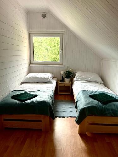 two beds in a room with a window at Siedlisko Nad Potokiem in Hołuczków