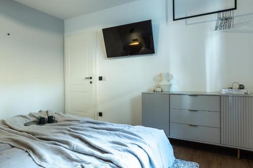 a bedroom with a bed and a dresser with a tv on the wall at Oskar Apartments in Neustift im Stubaital