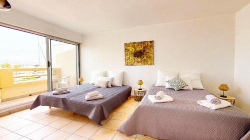 Duas camas num quarto com uma janela grande em Marina vue mer em Le Grau-du-Roi