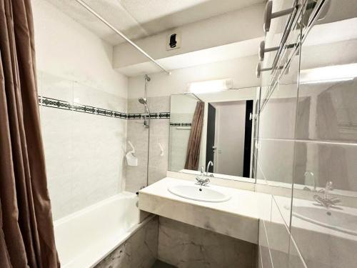 une salle de bain avec un lavabo, une baignoire et un miroir dans l'établissement Résidence Le Boucanier - 2 Pièces pour 4 Personnes 074, à Vieux-Boucau-les-Bains