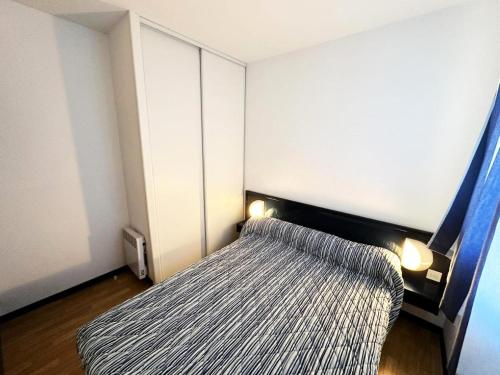 - une petite chambre avec un lit et une couverture rayée dans l'établissement Résidence Le Boucanier - 2 Pièces pour 4 Personnes 074, à Vieux-Boucau-les-Bains