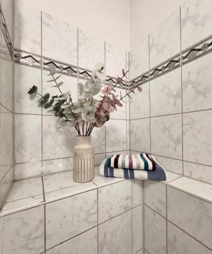 a vase with flowers on a shelf in a bathroom at Wohfühlen Garantiert Große Wohnung mit zwei Schlafzimmern und Terrasse in Görlitz