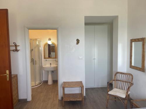 bagno con lavandino, sedia e specchio di Appartamenti in Villa Calamoni a Favignana
