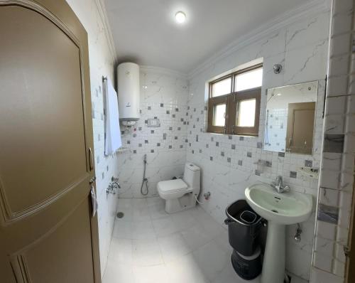 a white bathroom with a toilet and a sink at Hotel Inabat Residency in Srinagar
