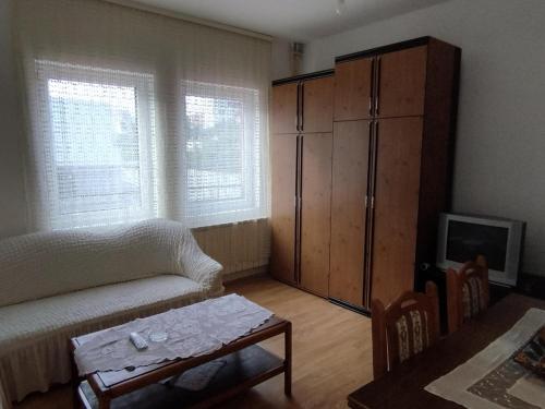 een woonkamer met een bank, een kast en een tafel bij MR Apartman in Belgrado
