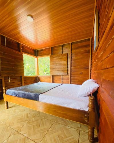 1 dormitorio con 1 cama en una habitación de madera en Cabaña Monarca en Turrialba