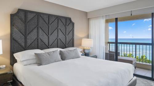 a bedroom with a large white bed and a balcony at Luxury Oceanfront 2 Bedroom Apartment at Waikiki Beach Tower in Honolulu