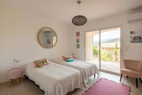 Cette chambre blanche dispose de deux lits et d'une fenêtre. dans l'établissement VILLA MYRTE A CIRINDINU, à Cirendinu