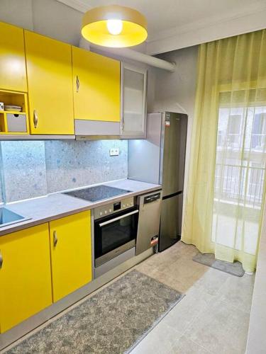 een keuken met gele kasten en een fornuis bij Yellow Kitchen Apartment, City Central location in Thessaloniki