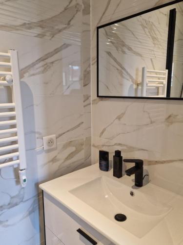 uma casa de banho branca com um lavatório e um espelho em Maison, 4 chambres, métro, climatisation em Villejuif
