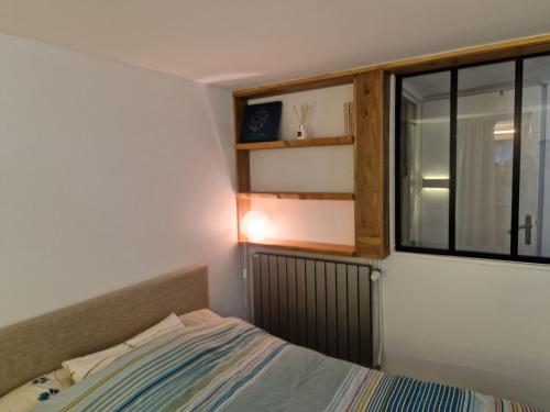um pequeno quarto com uma cama e uma janela em Maison, 4 chambres, métro, climatisation em Villejuif
