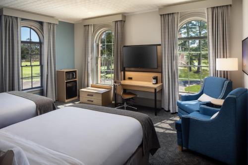 a hotel room with a bed and a desk and a tv at Hotel Ursa in Orono