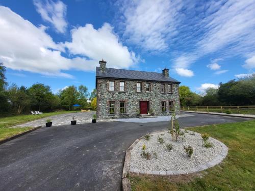uma velha casa de pedra com uma porta vermelha numa estrada em Reeks Country House em Killarney