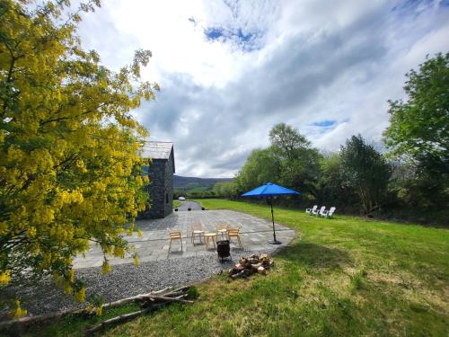 a patio with chairs and an umbrella on a field at Reeks Country House in Killarney
