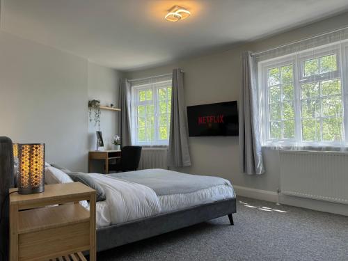 a bedroom with a bed and two windows and a desk at Luxury Apartment in Letchworth in Letchworth