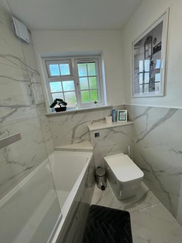 Luxury Apartment in Letchworth في ليتشوورث: حمام ابيض مع مرحاض ودش
