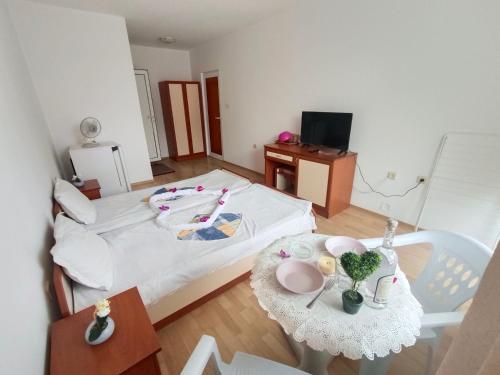 a small room with a bed with a table and a television at Стаи за гости Ники in Nesebar